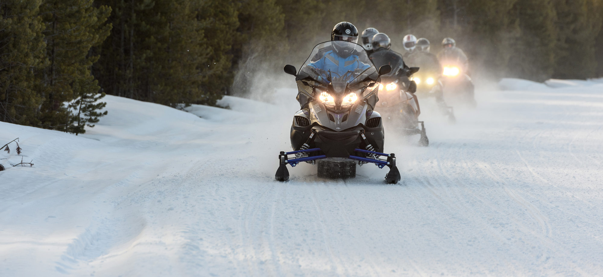 Snowmobilers riding in formation along trail