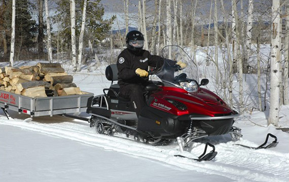 A snowmobiler towing a utlity sled
